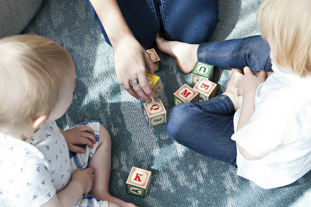 Caregiver and children playing with building blocks.